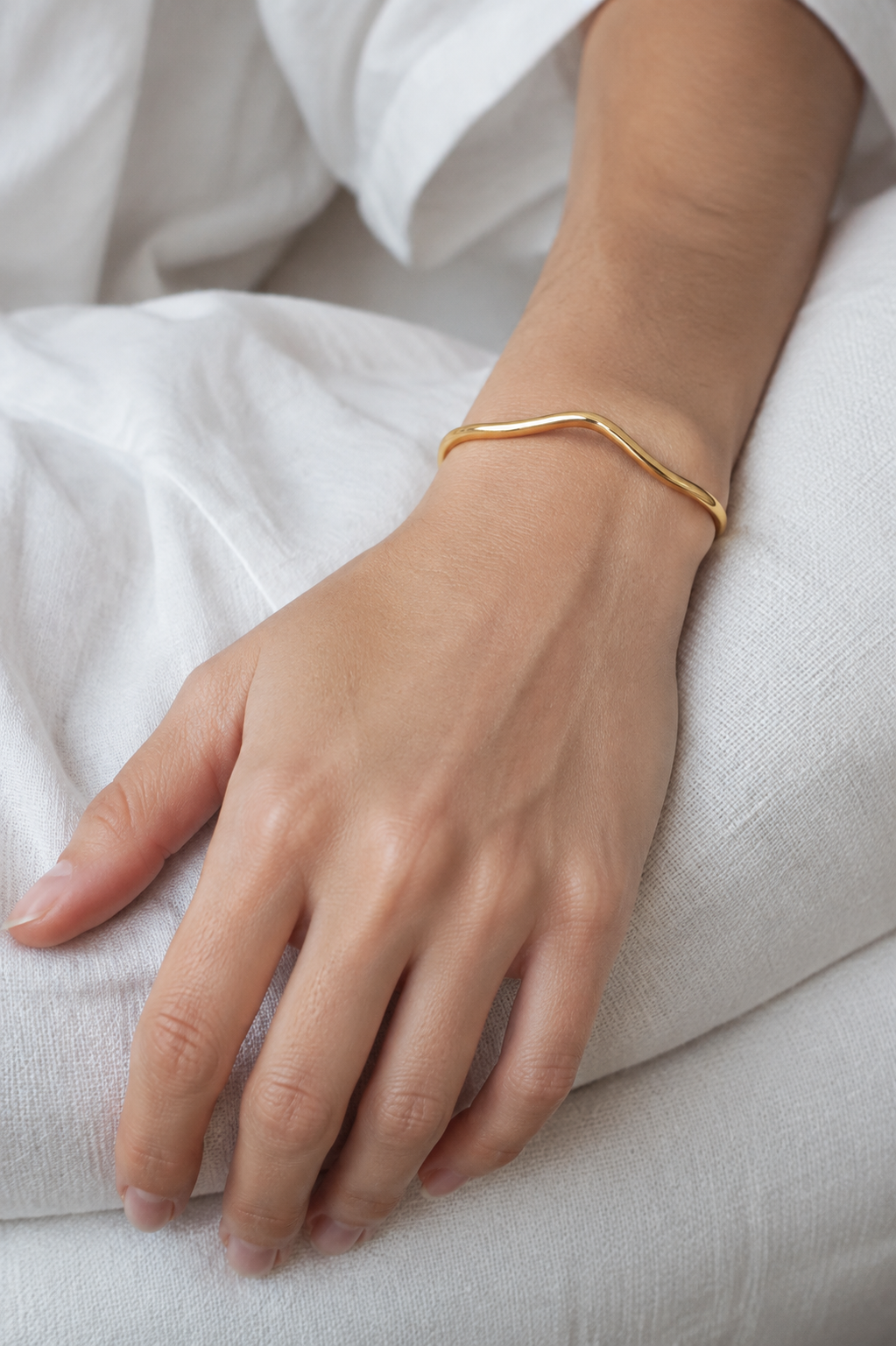 FLUID Cuff in gold worn on wrist — minimalist lifestyle view