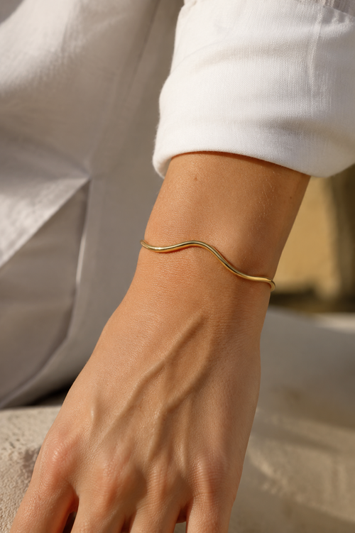 FLUID Cuff in gold worn on wrist in warm natural daylight